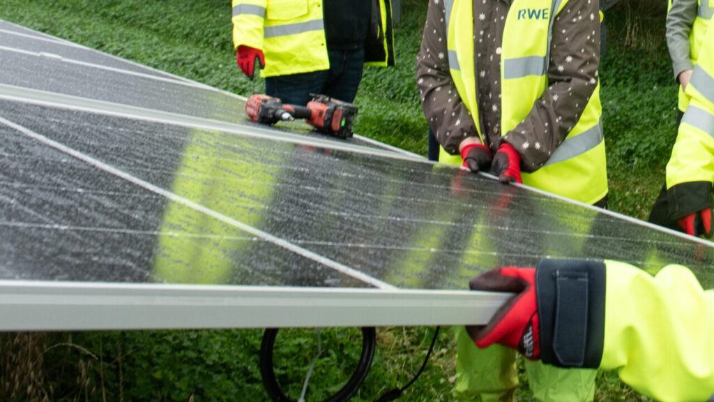 hands hold a solar panel with a drill on it
