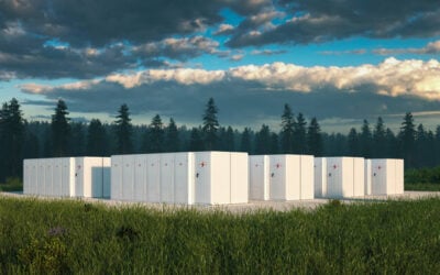 A battery energy storage system in front of trees underneath a blue sky with dark clouds