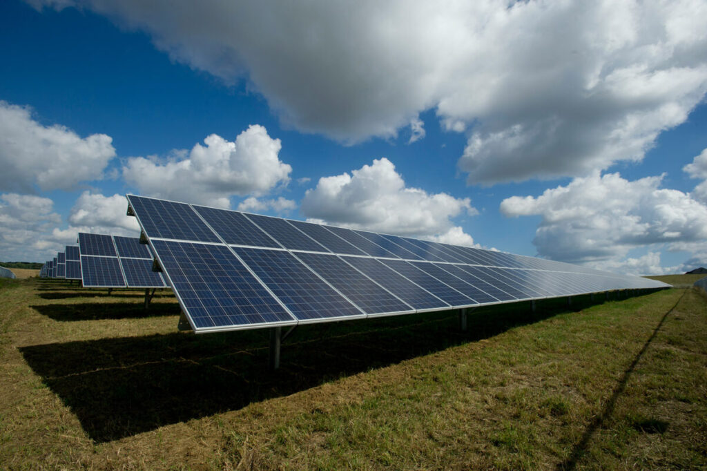 Image of solar PV modules in a field under cloudy sky