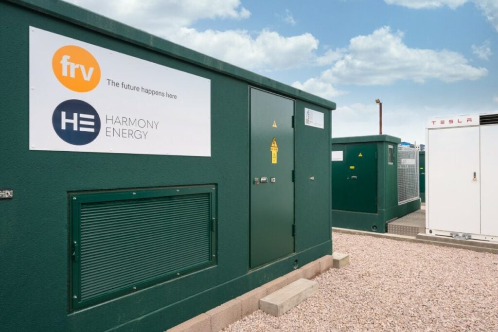 A dark green battery energy storage system, outside, under a blue sky