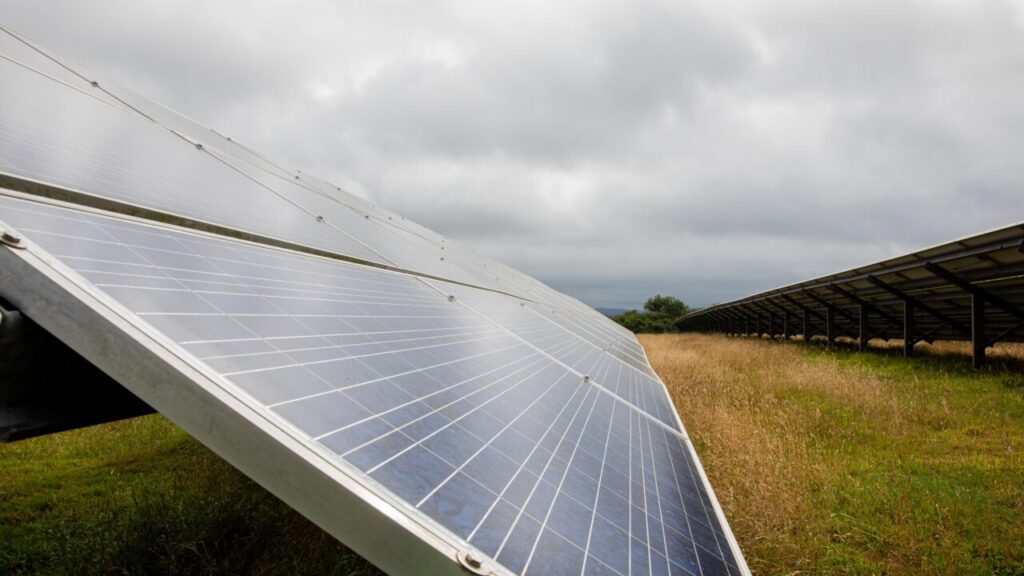 A solar panel in a field under a cloudy sky