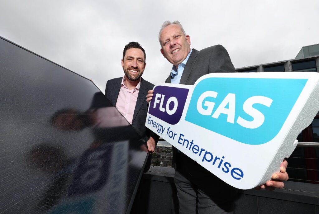 Two men hold the flogas logo next to a pv panel
